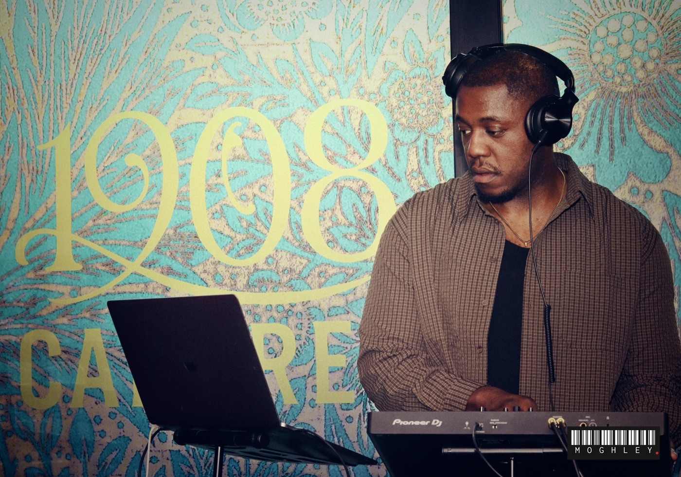 DJ performing in front of a colourful painted mural