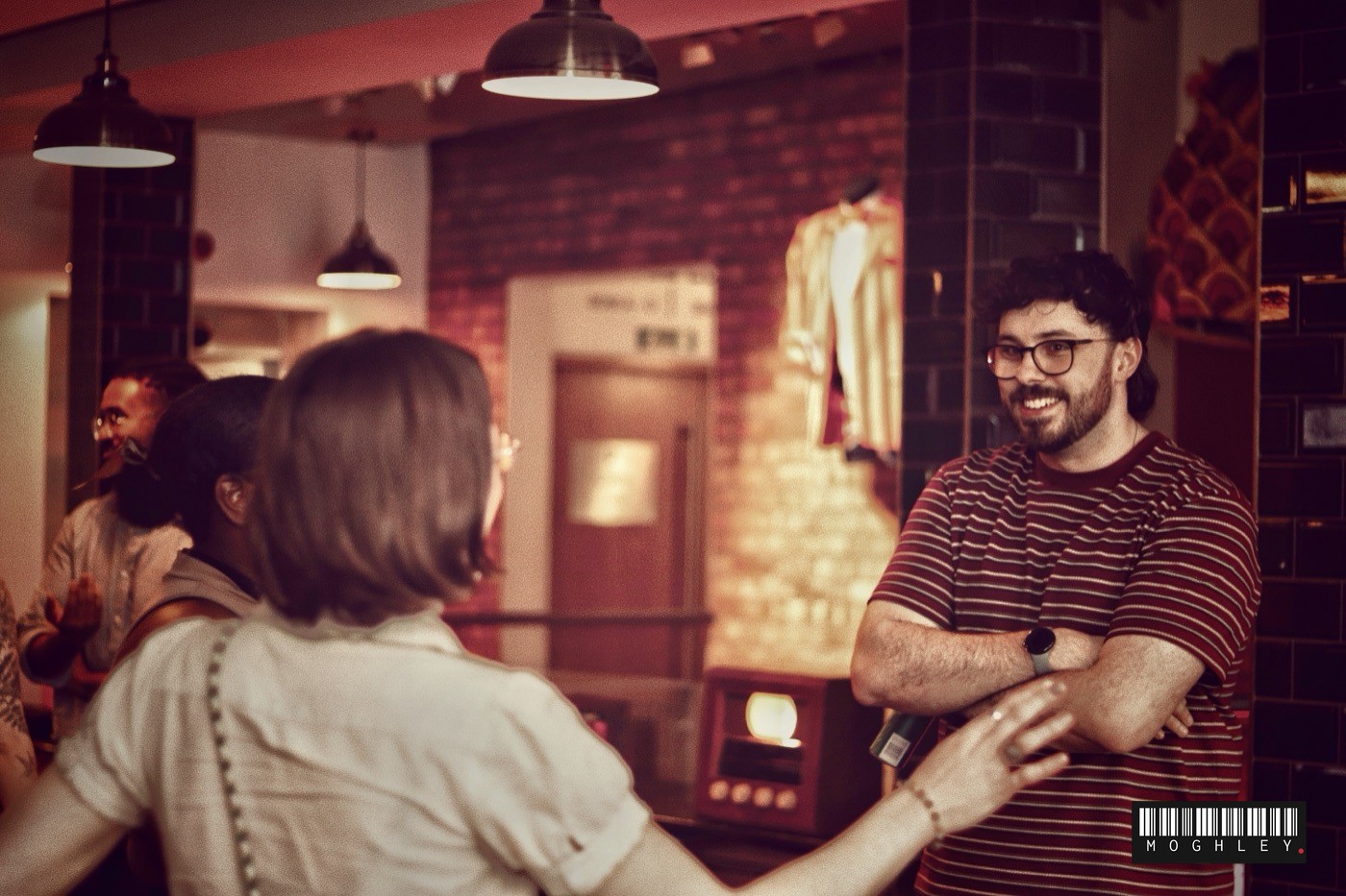 Two people greeting each other at an indoor bar or restaurant