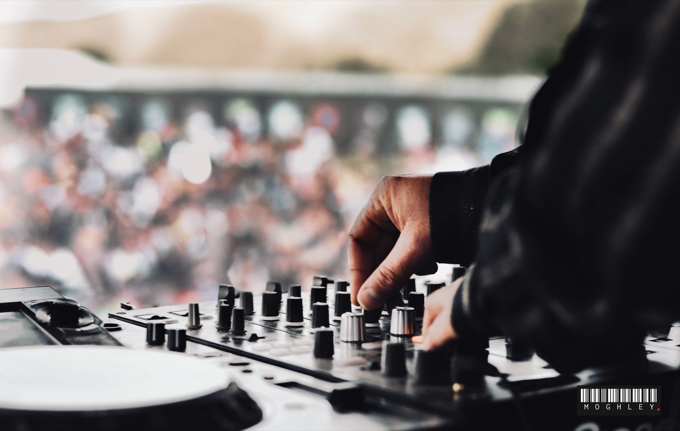 Close-up of a hand adjusting a DJ mixer at an outdoor festival